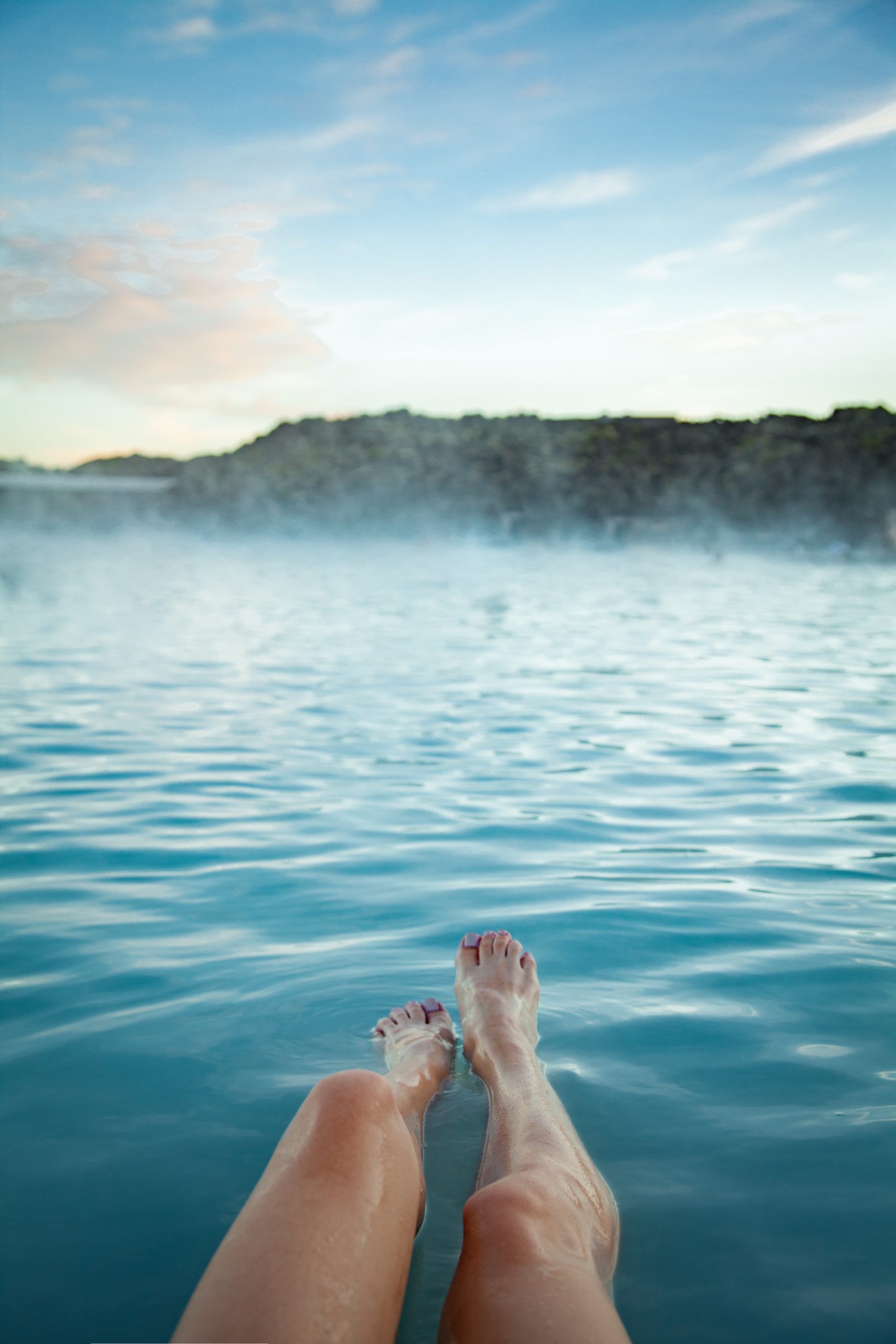 Still geothermal water at blue hour, steam drifting across the surface